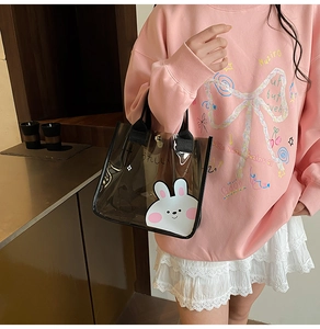 Détail du sac cabas en PVC noir translucide avec motif lapin tenu par le mannequin