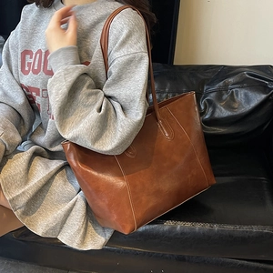 Minimalist large brown leather tote bag with long shoulder straps for casual commuting
