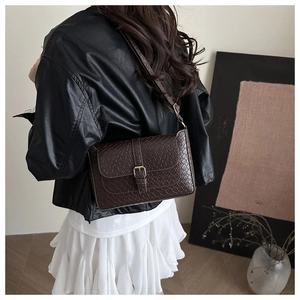 Detail of dark brown woven leather shoulder bag with vintage gold metal buckle
