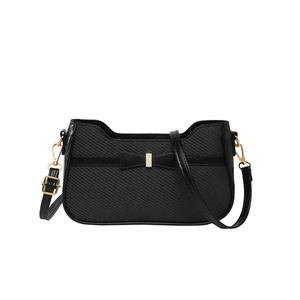 Minimalist black woven shoulder bag with a bow detail and gold hardware on white background