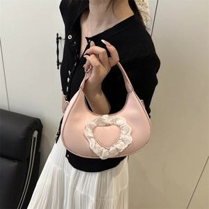 Pink crescent hobo bag with heart lace detail worn by model in elegant spring outfit
