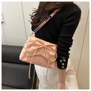 Gros plan du sac à bandoulière rose avec un nœud décoratif et une chaîne argentée