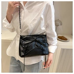 Détail du sac bandoulière noir avec nœud décoratif et bandoulière en chaîne argent
