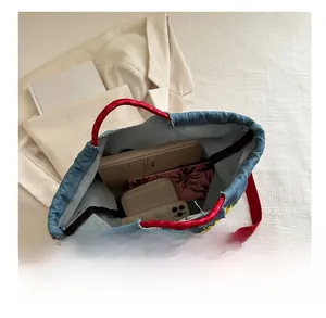 Internal capacity of denim tote bag showing books and phone inside blue canvas bag