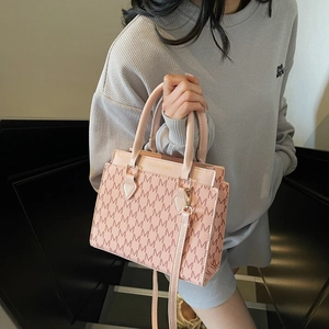 Pink monogram tote bag with top handles and logo print shown by model on stairs