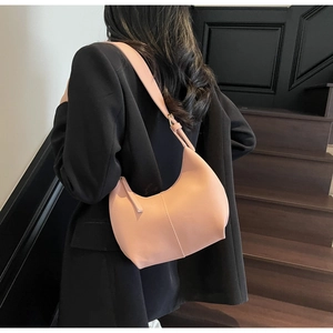 Detail of soft pink crescent shoulder bag against a black blazer for a stylish look