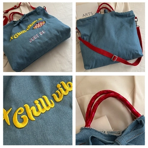 Detail of blue denim tote bag featuring yellow Chill Vibes embroidery and red strap
