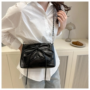 Détail d'un sac bandoulière noir en PU avec grand nœud et bandoulière chaîne cuir