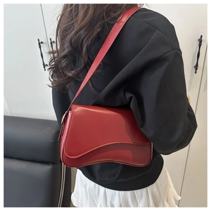 Detail shot of the red crossbody bag featuring a unique wavy flap and leather shoulder strap