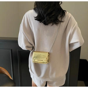 Detail of gold crocodile embossed mini square bag with silver chain strap on model
