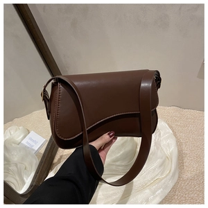Detailed view of dark brown leather flap bag with fine stitching and metal buckle details