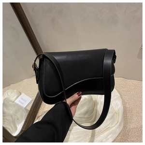 Close-up of black retro saddle bag with matte leather finish and wide shoulder strap