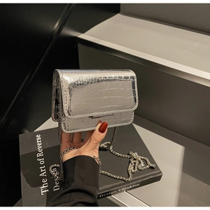 Detail of silver crocodile-textured crossbody bag with metallic finish and chain strap