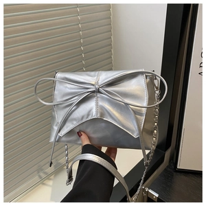 Vue détaillée du sac bandoulière argenté métallisé avec grand nœud décoratif et chaîne