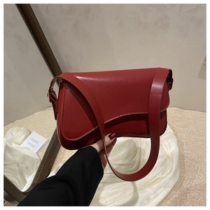Detail of red leather crossbody bag with flap closure and stylish wide shoulder strap