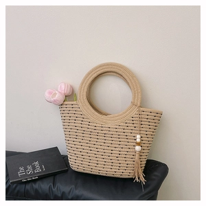 Dettaglio della borsa a secchiello intrecciata beige con strisce nere e nappine in rilievo