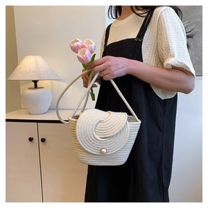 Détail du sac bandoulière tissé avec motifs en spirale et fermoir perle centrale