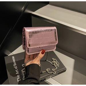 Detail of metallic pink crocodile embossed square bag with a silver chain strap