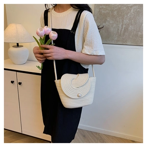 Détail du sac seau tissé avec motif en spirale et fermoir en perle pour vacances à la plage