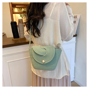 Détail d'un sac seau tissé vert clair avec boucle en perle et rabat en spirale