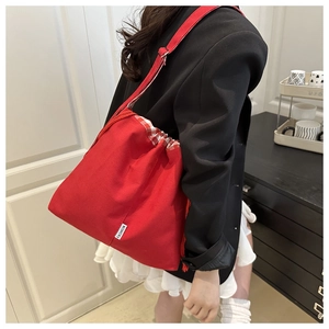 Detail of red canvas drawstring bucket bag with checkered fabric trim and fashion label
