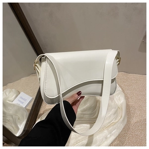 Detail of cream white baguette bag with asymmetrical curved flap and matte leather texture