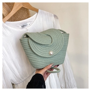 Détail du sac seau en paille tissée verte doté d'un grand bouton en perle blanche
