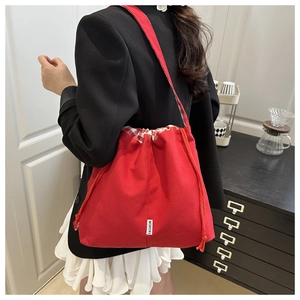 Detail of red canvas bucket bag with drawstring closure and red checkered fabric trim