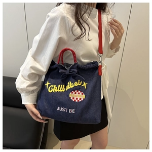 Detail of blue denim tote bag with red handles and yellow Chill vibes embroidery
