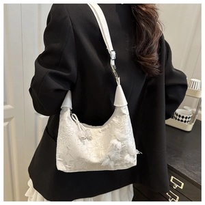 Detail of white lace shoulder bag with 3D floral accents worn over a black blazer