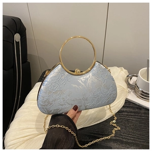Detail der hellblauen Halbmond-Tasche mit Blumenmuster und goldener Metallgriff