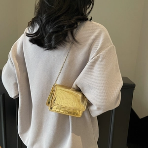 Golden crocodile embossed crossbody bag with silver chain strap shown on model waist