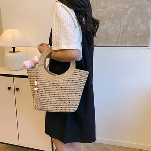 Borsa a secchiello intrecciata minimalista con manici tondi e nappina con perline