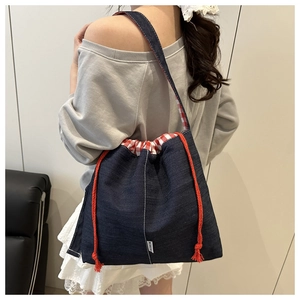 Detail of denim bucket bag showing red drawstring closure and red checkered lining