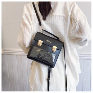 Detail of black leather crossbody bag with clear window and gold buckle on model