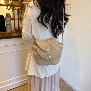 Sac seau en paille tressée beige avec rabat à spirale perlé dans un café chaleureux