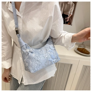 Detail of light blue lace bucket bag featuring 3D butterfly decor and leather strap