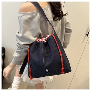 Detail of blue denim bucket bag featuring red drawstring and checkered fabric lining