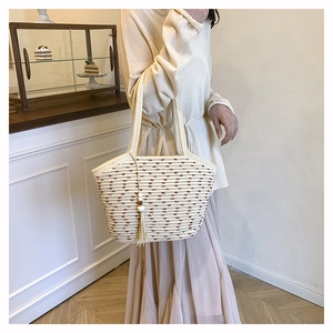 Detail of woven tote bag featuring beige texture with brown dots and tassel accent
