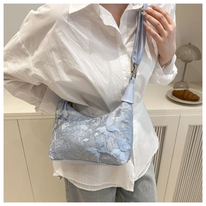Detail of light blue crossbody bucket bag featuring floral lace and 3D butterfly appliques