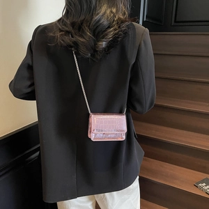 Pink croc-effect mini square bag with silver chain strap shown on a black blazer