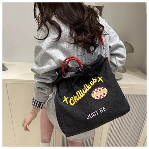 Detail of black denim tote bag featuring yellow Chillvibes embroidery and red rope handle