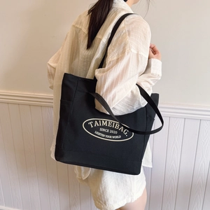 Borsa tote minimalista in tela nera con tracolla e logo bianco per il pendolarismo