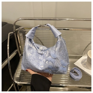 Close-up of light blue lace bucket bag featuring 3D butterfly details and leather handle
