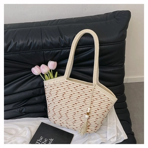 Detail of woven beige tote bag featuring brown polka dots and wooden bead tassel