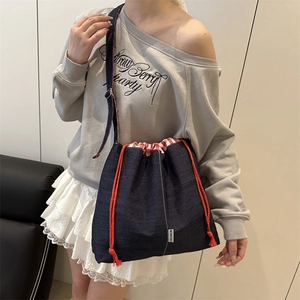 Deep blue denim drawstring bucket bag with FASHION label and red plaid lining