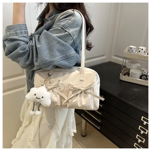 Détail d'un sac oreiller blanc cassé avec poches à nœuds et pendentif nuage en peluche