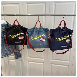 Detailed close-up of three denim tote bags with red handles and colorful embroidery