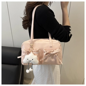 Détail du sac bandoulière rose clair avec nœuds et breloque en peluche nuage