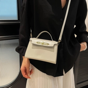 Minimalist cream white square crossbody bag with gold buckle shown on model